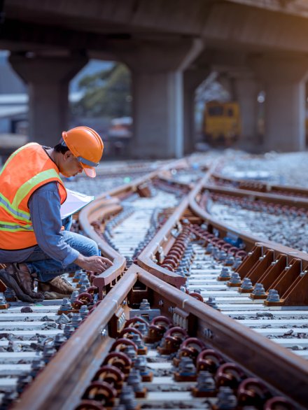 Portrait engineer under inspection and checking construction process railway switch and checking work on railroad station .Engineer wearing safety uniform and safety helmet in work.